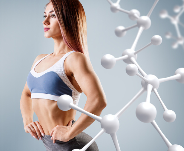 Sporty young woman posing near molecules structure. - Photo, Image