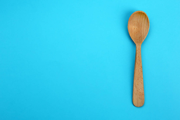 Clean empty wooden spoon on blue background, top view. Space for text - Fotoğraf, Görsel