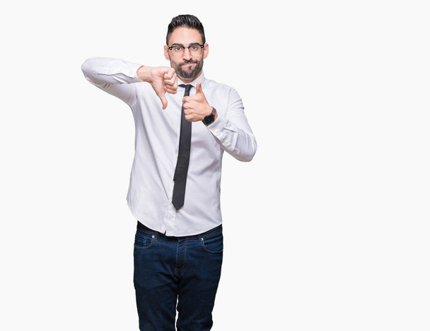 Young handsome business man wearing glasses over isolated background Doing thumbs up and down, disagreement and agreement expression. Crazy conflict - Photo, Image
