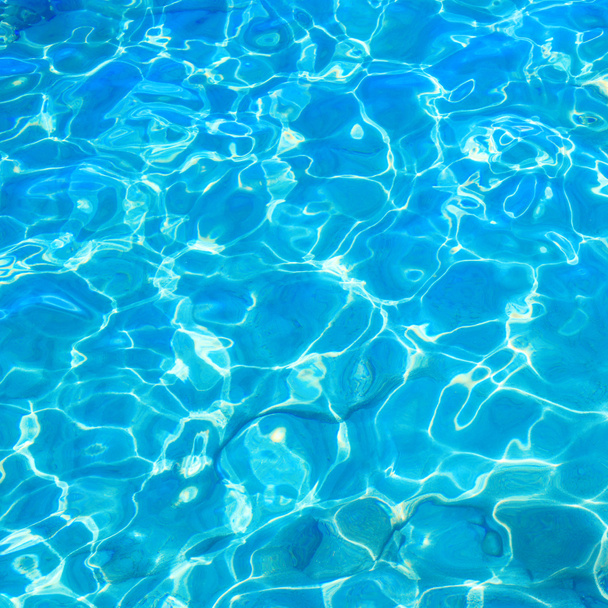 blaues klares Wasser mit welliger Oberfläche und Sandboden. - Foto, Bild