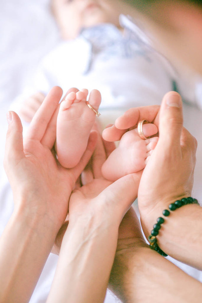 Children's feet in hands of mother and father. Mother, father and Child. Happy Family concept. Beautiful conceptual image of Motherhood - Photo, Image