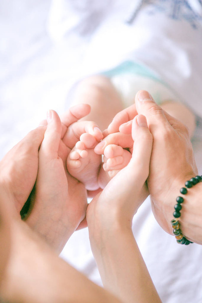 Gyermekláb a kezében anya és apa. Anya, apa és gyermeke. Boldog család koncepció. Gyönyörű fogalmi kép az anyaság - Fotó, kép
