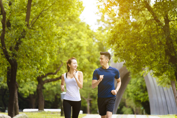glückliches junges Paar joggt und läuft im Park - Foto, Bild