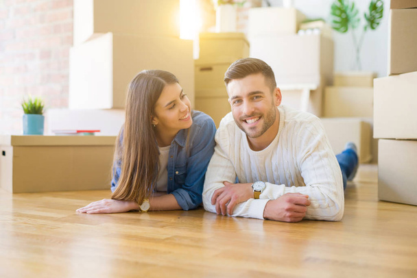 Молодая красивая пара лежит на полу нового дома, улыбается в любви и очень рада переезду в новую квартиру
 - Фото, изображение