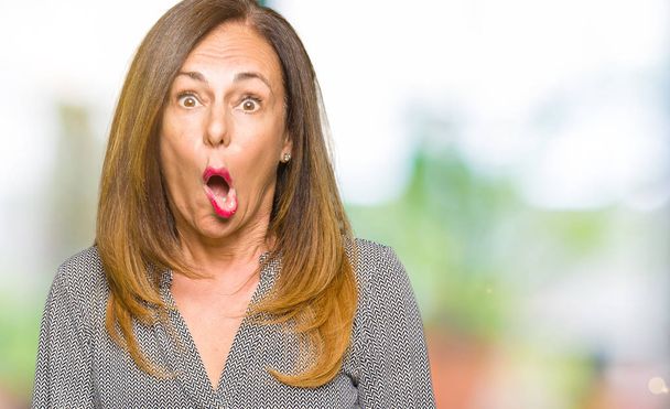 Beautiful middle age business woman In shock face, looking skeptical and sarcastic, surprised with open mouth - Photo, image
