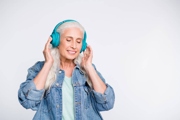 Portrait of pretty old lady closing eyes touch headset isolated over white background - Foto, Imagen
