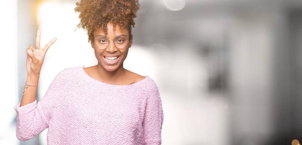 Mooie jonge african american vrouw dragen bril over geïsoleerde achtergrond weergeven en met de vingers omhoog nummer twee terwijl lacht zelfverzekerd en blij. - Foto, afbeelding