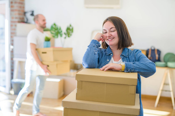Young couple moving to a new home, smiling happy holding cardboard boxes - Photo, Image