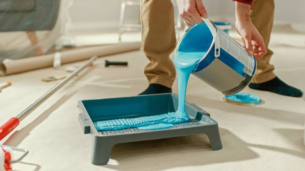 Close Up Shot of a Man applying Light Blue Paint on a Roller with Long Handle. Paint is in the Tray. Room Renovations at Home. - 写真・画像