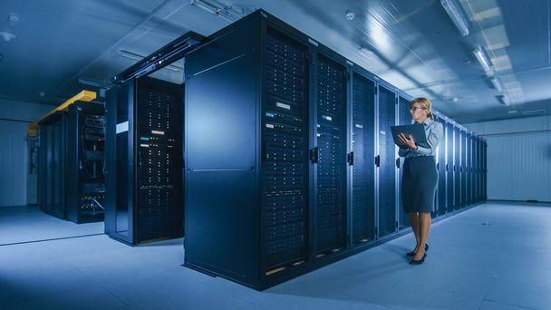 In Data Center Female IT Specialist Walks along the Row of Operational Server Racks, Checking Normal Functioning. Modern High-Tech Telecommunications Operational Data Center. - Photo, image