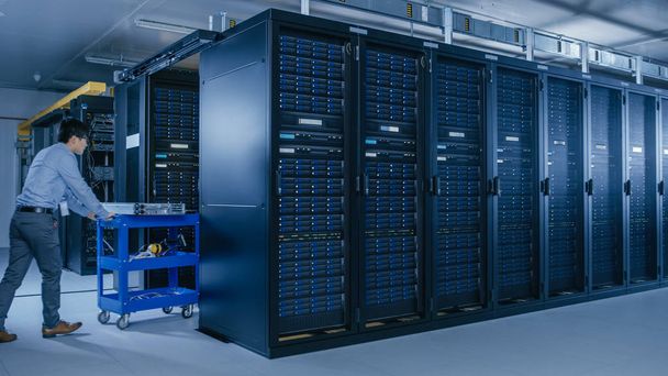 In the Modern Data Center: Team of IT Technicians Working with Server Racks, Running Maintenance and Diagnostics, Checking Networking and Cloud Computing Optimal Functioning. - Photo, Image
