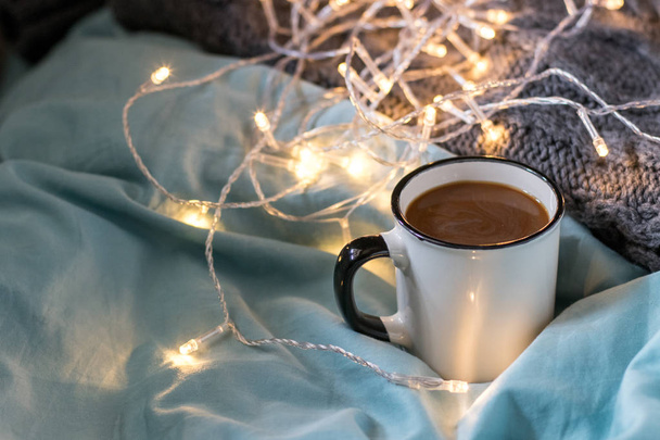 Kaffeetasse und Girlande auf einem Bett. atmosphärisch schwedischer Hygge-Stil - Foto, Bild