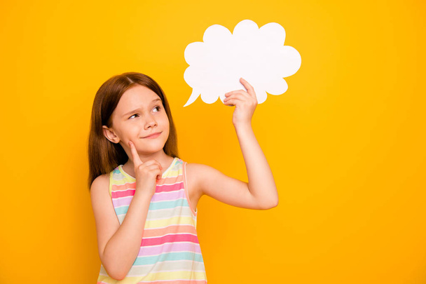 Portrait lovely kid holding paper card bubble touching chin wearing tank-top isolated over yellow background - Zdjęcie, obraz