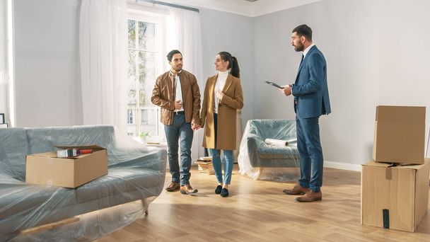 Professional Real Estate Agent Shows Bright New Apartment to a Young Couple. Successful Young Couple Ready to Become Homeowners. Spacious Bright Home with Big Windows. - Foto, Bild
