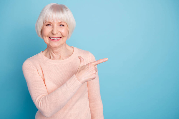 Portrait of pretty lady pointing at copy space smiling wearing pastel jumper isolated over blue background - Fotoğraf, Görsel