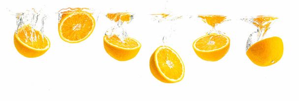 Kilka organicznych połówki pomarańczy toną w krystalicznie czyste wody z pęcherzyków powietrza. Widok panoramiczny - Zdjęcie, obraz
