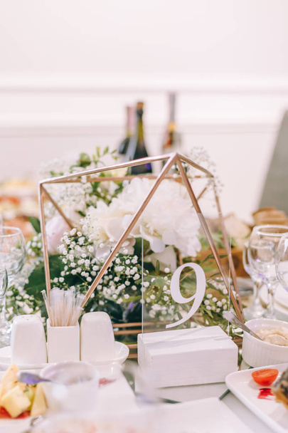 表番号 9.結婚式のテーブル。硬化テーブル。ラウンドバンケットテーブルが出てきます。結婚式のディナーのためのレストランのインテリア、ゲストのための準備ができています。花柄で装飾されています。ワイングラスとナプキン. - 写真・画像