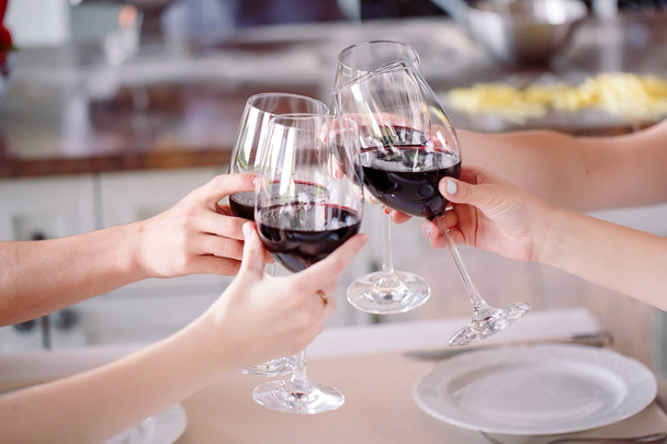 Νέοι άνθρωποι σε ένα εστιατόριο πίνοντας κρασί στο φόντο ένας μάγειρας που προετοιμάζει - Φωτογραφία, εικόνα