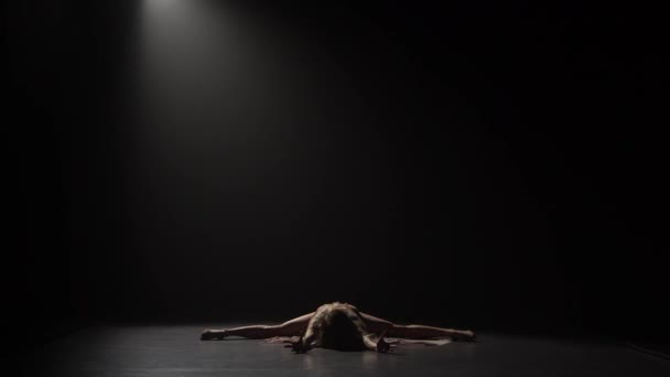 Silhouette of graceful girl dancing and sitting on splits at studio - Felvétel, videó