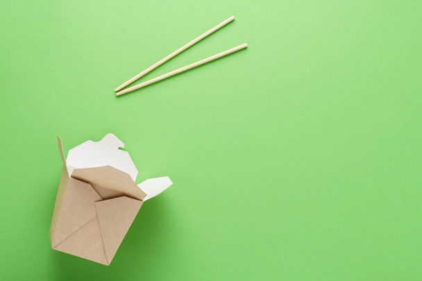 Open empty kraft paper box and chopsticks on green background. - Valokuva, kuva