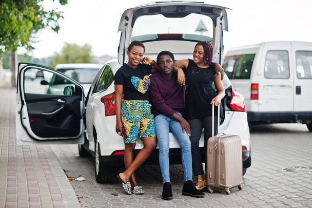 Tři afričtí američtí přátelé sedí v kufru auta. - Fotografie, Obrázek