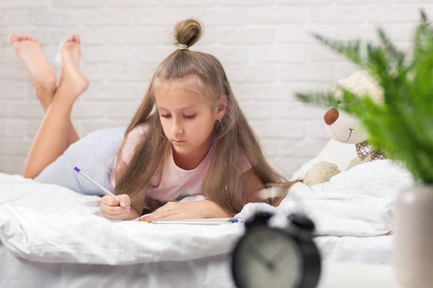 cute little girl drawing pictures while lying on bed - Fotoğraf, Görsel