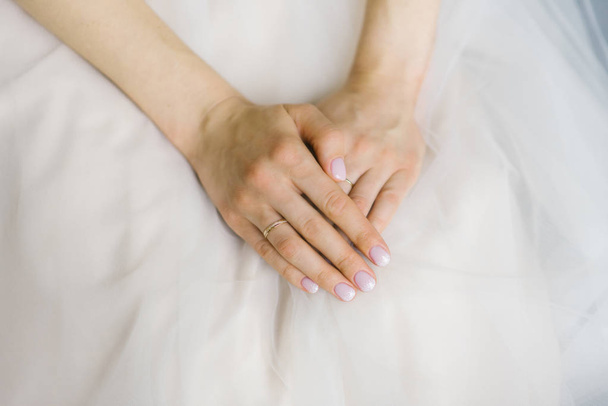 Gelin elleri katlanmış ve gelinliğin üzerinde yalan, düğün manikür ve düğün yüzüğü parmak üzerinde - Fotoğraf, Görsel