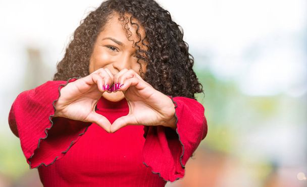Young beautiful woman with curly hair smiling in love showing heart symbol and shape with hands. Romantic concept. - Photo, Image