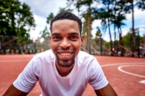Молодий чорний баскетболіст посміхається в камеру
 - Фото, зображення