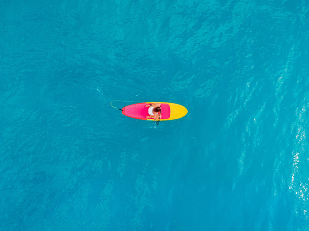 Sessiz mavi bir denizde ayakta duran kürek tahtasında dinlenen kadın. Aer - Fotoğraf, Görsel