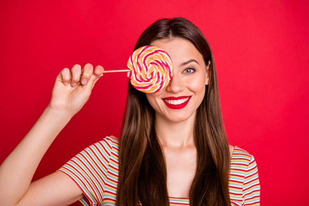 Close-up photo of glad positive nice charming dream dreamy lady teenager holding swirly caramel candy in hand isolated vivid background - Foto, Imagen