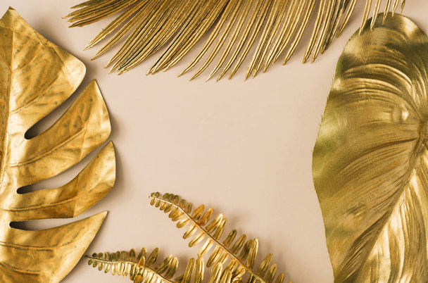 Creative layout made of golden tropical  palm leaves on pastel beige background. Minimal summer exotic concept  - 写真・画像