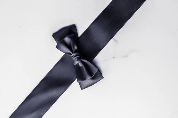 Black silk ribbon and bow on marble background, flatlay, Stock image