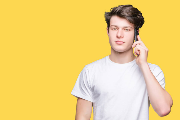 Young man talking on smartphone over isolated background with a confident expression on smart face thinking serious - Photo, Image