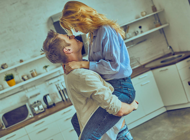 Romantic young couple cooking together in the kitchen, having a great time together.  - Fotó, kép