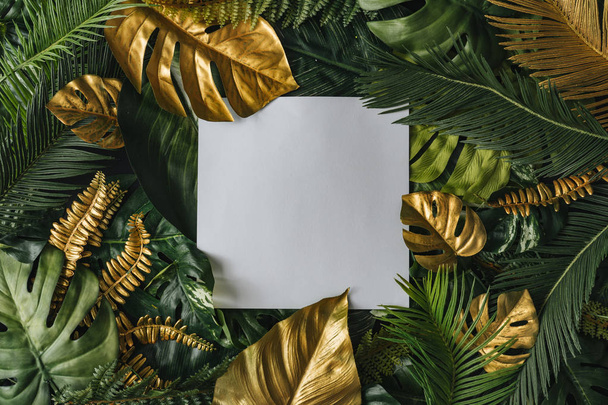Fundo de natureza criativa de ouro e folhas de palma tropicais verdes com nota de cartão de papel branco. Padrão mínimo de verão selva abstrata
 - Foto, Imagem