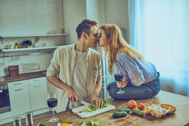 Happy couple cooking healthy food and drinking red wine at house kitchen - Fotoğraf, Görsel