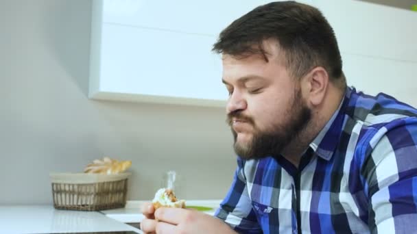 An overweight man eats his hamburger and drinks carbonated soft beverage. Guy enjoys the homemade food. Unhealthy Lifestyle, fried and harmful high calorie food. The risk of obesity and overweight. - Záběry, video
