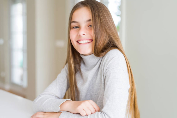 Szép fiatal lány gyerek viselt garbó pulóvert egy boldog és hűvös mosoly az arcon. Szerencsés ember. - Fotó, kép