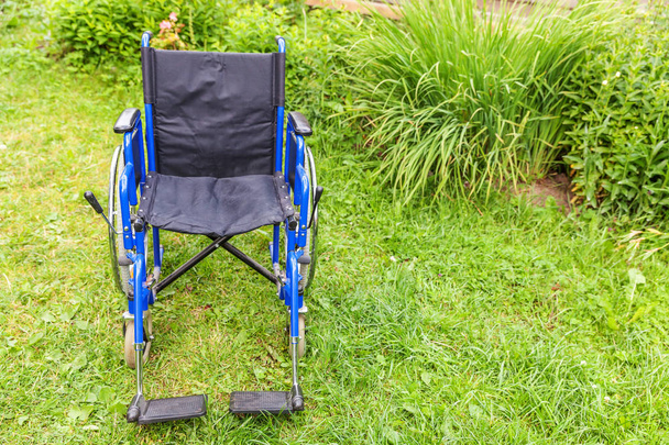 Silla de ruedas vacía de pie sobre hierba en el parque del hospital esperando por los servicios del paciente
 - Foto, imagen