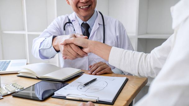 Médico masculino profesional en bata blanca estrechando la mano con la mujer
  - Foto, Imagen