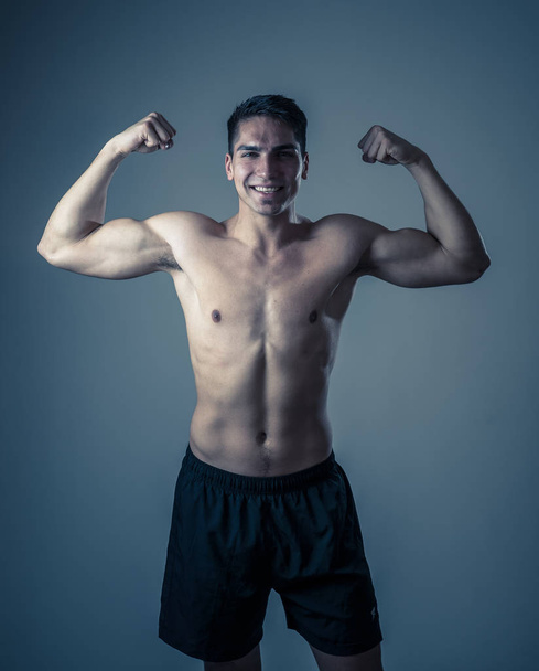 Portrait of strong handsome Athletic man isolated on neutral background. Mixed race latin fitness model posing showing biceps and strong body. In exercise, healthy lifestyle, workout and body care. - Φωτογραφία, εικόνα