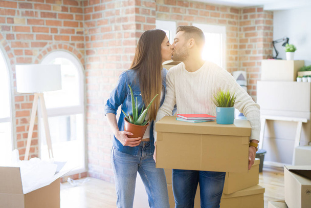 Beautiful young couple moving to a new house, smiling happy holding cardboard boxes at new apartment - 写真・画像
