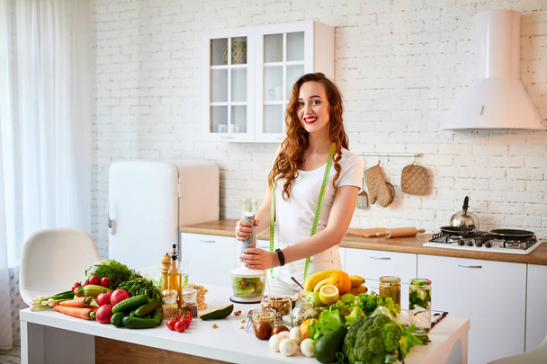 Young happy woman preparing tasty salad in the beautiful kitchen with green fresh ingredients indoors. Healthy food and Dieting concept. Loosing Weight - Fotografie, Obrázek