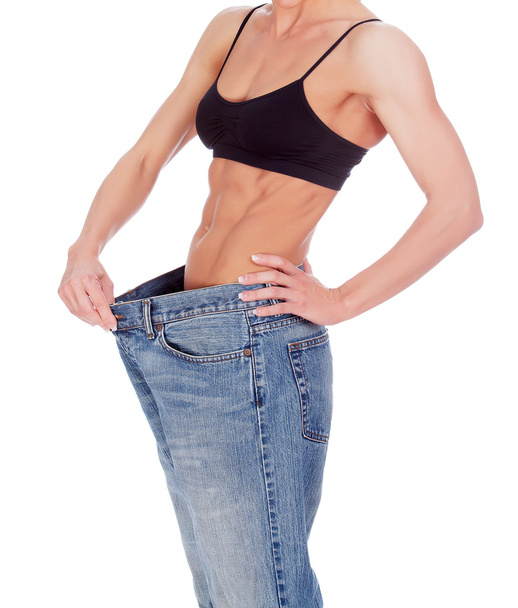Frau zeigt ihren Gewichtsverlust, indem sie eine alte Jeans trägt - Foto, Bild