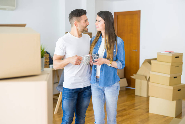 Beautiful couple moving to a new house, smiling cheerful drinking a cup of coffee - Photo, Image