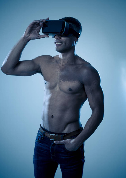 Atractivo hombre africano musculoso fuerte usando gafas VR aumentadas, sintiéndose entusiasmado con la simulación explorando nuevas experiencias. En realidad virtual, entrenamiento virtual y nuevo concepto de tecnología
. - Foto, imagen