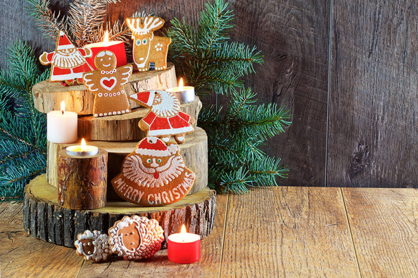 On a light wooden background with branches of fir-tree with decorations are arranged wooden stands with Christmas gingerbread and gifts. - Φωτογραφία, εικόνα