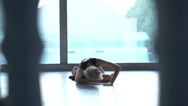Mooi blond meisje liggend en Rolling tijdens het dansen overweegt in een studio in slo-mo - Video