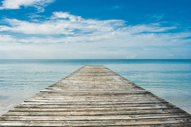 Beautiful seascape tropical view of Wooden bridge bring to the sea with blue sky in summer seasonal. - Photo, Image